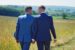 Homosexualität und Islam: Zwei Männer in Anzügen, die über ein Feld an einem sonnigen Tag spazieren, während sie Händchen halten